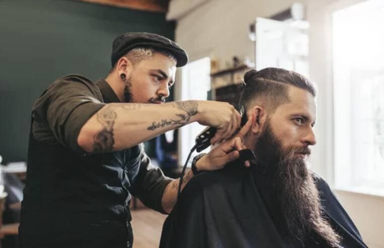 A barber trimming a client's hair and beard