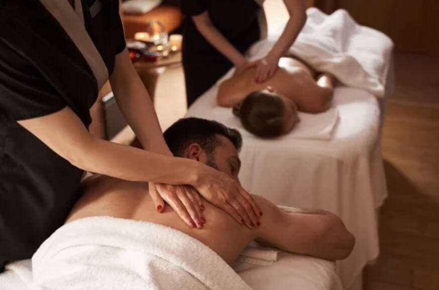 Massage therapists working on clients in a spa treatment room